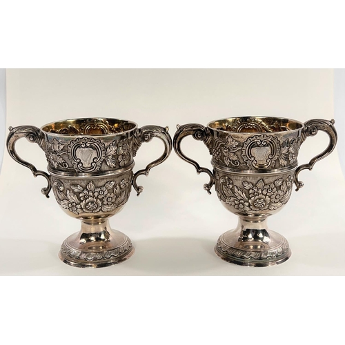 731 - A hallmarked silver pair of Irish cast loving cups with twin handles, extensive relief decoration of... 