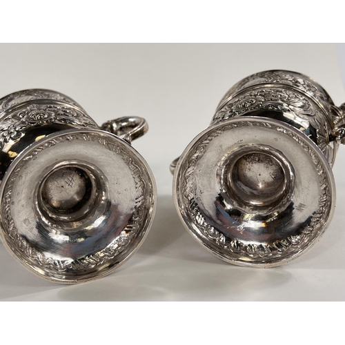 731 - A hallmarked silver pair of Irish cast loving cups with twin handles, extensive relief decoration of... 