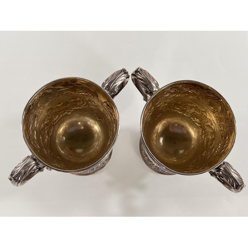 731 - A hallmarked silver pair of Irish cast loving cups with twin handles, extensive relief decoration of... 