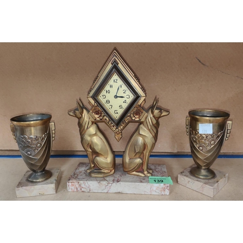 139 - An Art Deco clock garniture in bronzed metal, comprising diamond shaped clock supported on seated do... 