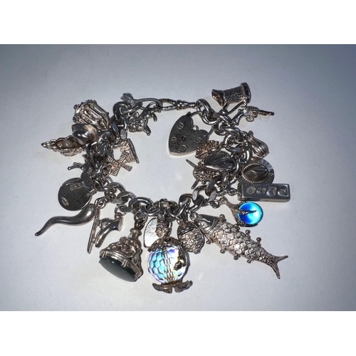 618 - A silver coloured charm bracelet with hallmarked silver lock, some charms hallmarked (25 charms) 3.7... 