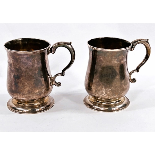 702 - A Georgian hallmarked silver pair of baluster half pint mugs with scroll handles and raised circular... 