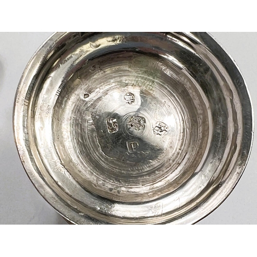 702 - A Georgian hallmarked silver pair of baluster half pint mugs with scroll handles and raised circular... 