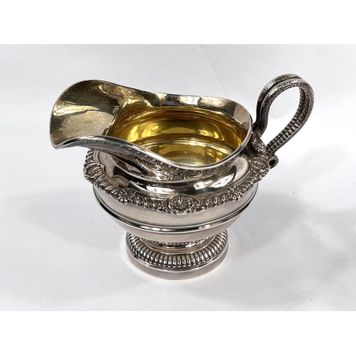 704 - A Georgian style hallmarked silver milk jug and sugar bowl of circular form with gadrooned and shell... 