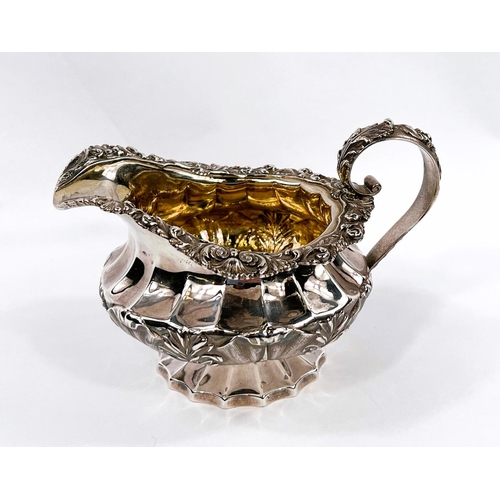 705 - A late Georgian hallmarked silver cream jug of ribbed squat form with acanthus and shell border, on ... 