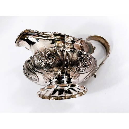 705 - A late Georgian hallmarked silver cream jug of ribbed squat form with acanthus and shell border, on ... 