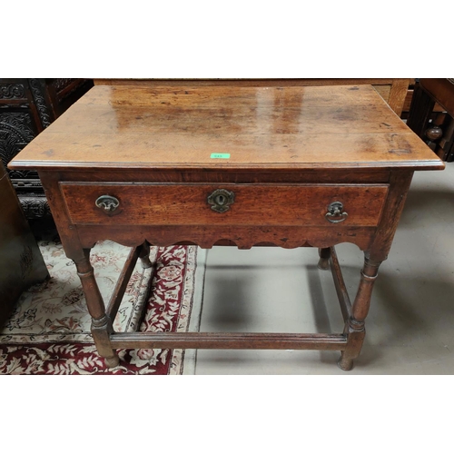 945 - An early 18th century country made oak side table with frieze drawer and scalloped apron, on turned ... 