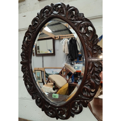 962 - An early 20th century oval bevelled glass wall mirror with carved and pierced decoration, 71 x 55cm