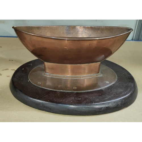 18B - An Arts & Crafts copper table centre in the form of a boat, on a wooden stand, Length 33cm