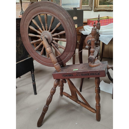 963 - An antique wooden treadle spinning wheel with carved name Isabel. C. Birkbeck