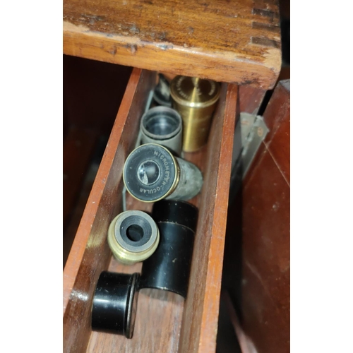 51 - A cased mahogany japanned metal microscope with three lenses, other spares, named H.F Angus & Co... 