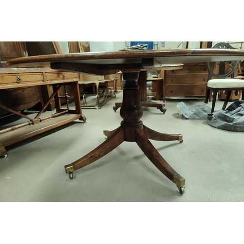 1017 - A circular period style oak pedestal dining table on turned baluster column, 4 splay feet and brass ... 