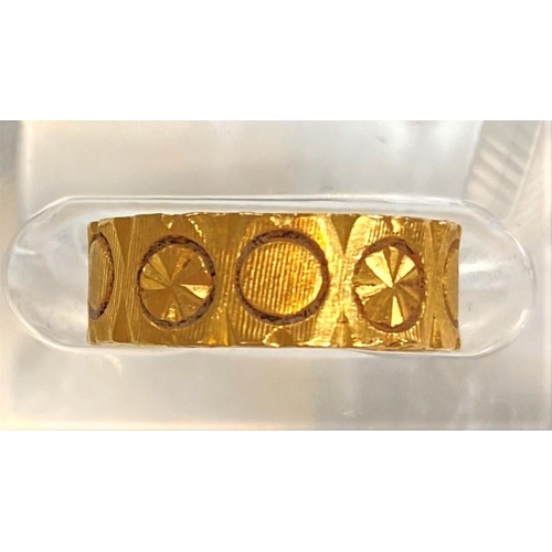 657A - A wedding ring decorated with circular motifs, unmarked, tests as 18ct+, 4gm