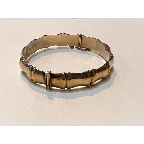 629 - A 9ct gold bangle of shaped bamboo form with safety chain, hinged, 12.4gms