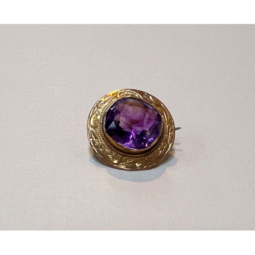 643 - A yellow metal brooch with large central faceted amethyst coloured stone in shield shaped mount with... 