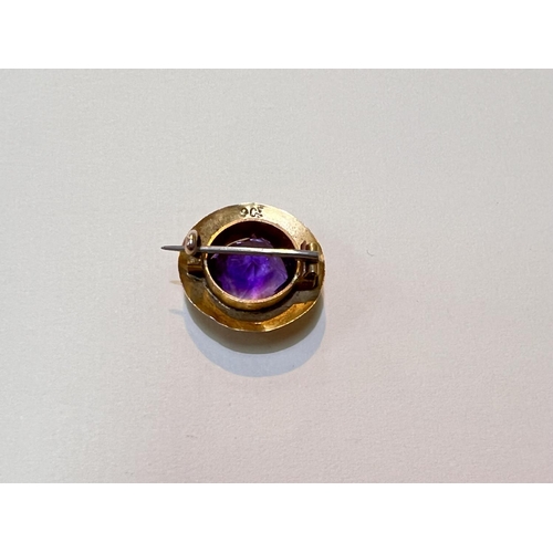 643 - A yellow metal brooch with large central faceted amethyst coloured stone in shield shaped mount with... 