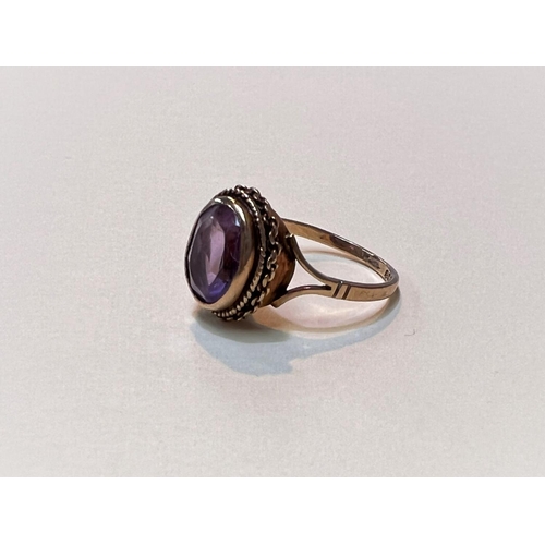 645 - A 9ct gold ring with an oval faceted stone and a roped border, size L, weight 2.6gms.