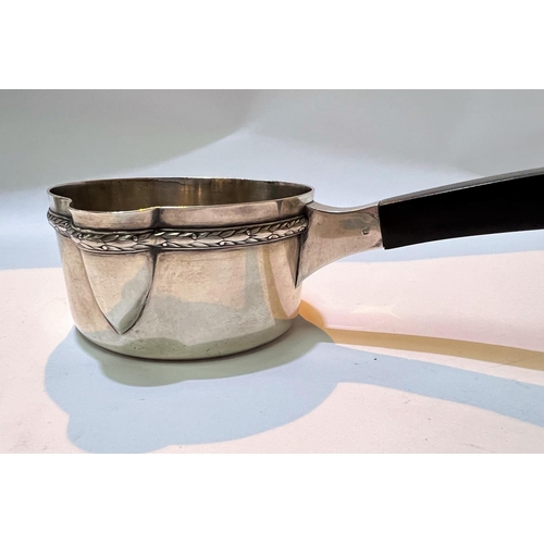 701 - A 19th century white metal, possibly French, brandy sauce pan with ebonised squared handle, with rel... 