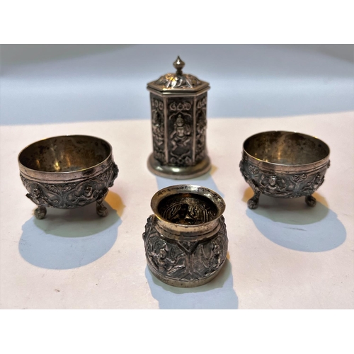 702 - An Indian white metal four piece cruet set with relief decoration of deities etc, salts, pepper and ... 