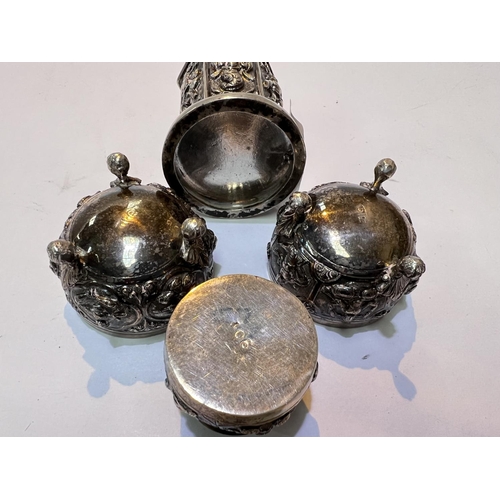 702 - An Indian white metal four piece cruet set with relief decoration of deities etc, salts, pepper and ... 