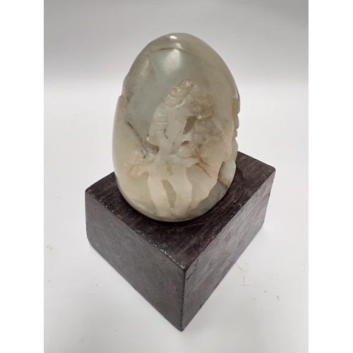 459B - A Chinese Jade coloured hard stone, carved egg shaped piece with carved decoration with cave like fo... 