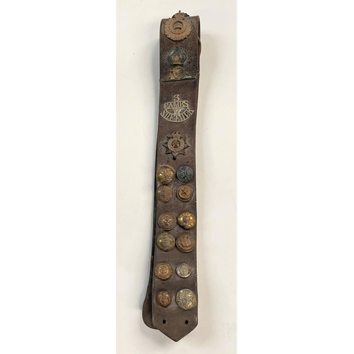 377 - A WWI belt with various badges and buttons attached 