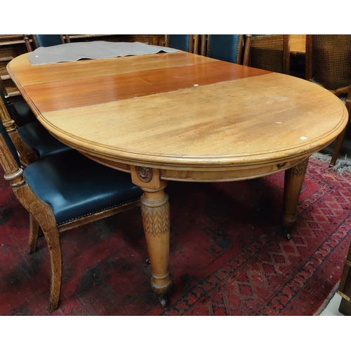 985 - An oval stained wood wind out dining table on carved baluster legs & castors, 2 spare leaves.