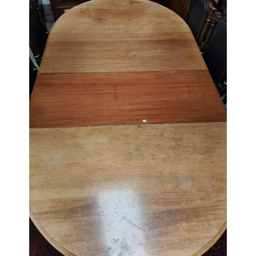 985 - An oval stained wood wind out dining table on carved baluster legs & castors, 2 spare leaves.