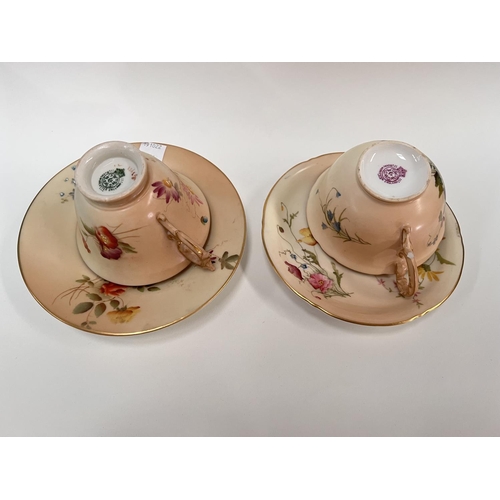 594 - Two Royal Worcester cabinet cups and saucers decorated in polychrome against a peach blush ground