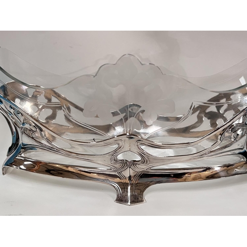 690A - A WMF Art Nouveau table centre in a boat shape with centre etched floral decoration, two Putti figur... 