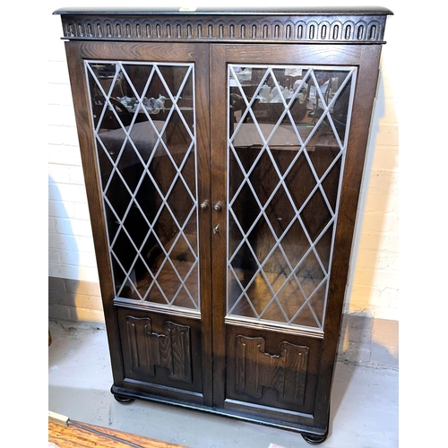 949 - An Ercol modern display cabinet/bookcase with double leaded glass doors over linen fold panel doors