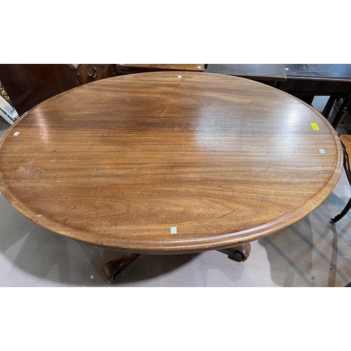 957 - An oval tilt top mahogany supper table with base, 121cm.