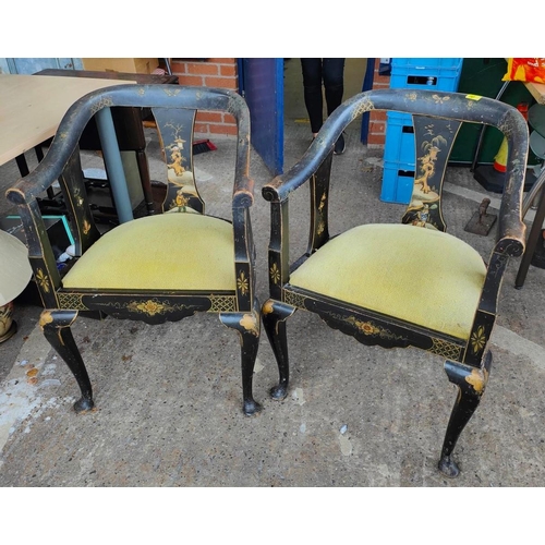 1008 - A Chinese pair of tub chairs decorated iin black & gilt with flowers and traditional scenes