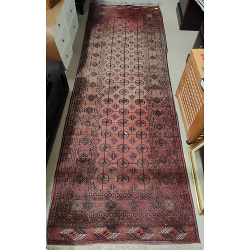 929 - A Middle Eastern rust ground long rug with three lines of medallions, multiple borders etc 296 x 105... 