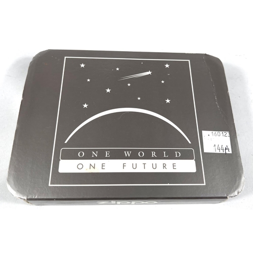 144A - A Zippo lighter 'One World One Future', in original tin and slipcase, boxed