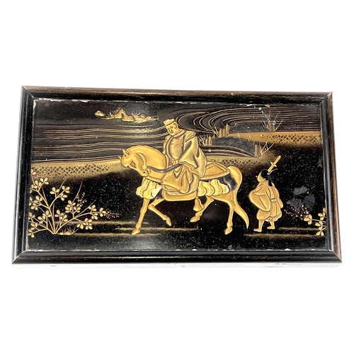 391 - A Japanese black lacquer and gilt plaque depicting a man on horseback, 10 x 19cm