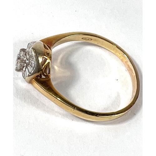 708 - A lady's gold dress ring set with central diamond surrounded by a wavy band of baguette diamonds, ce... 