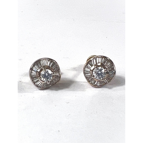 709 - A pair of diamond earrings with central diamond, diameter approx. 4mm, surrounded by a wavy band of ... 