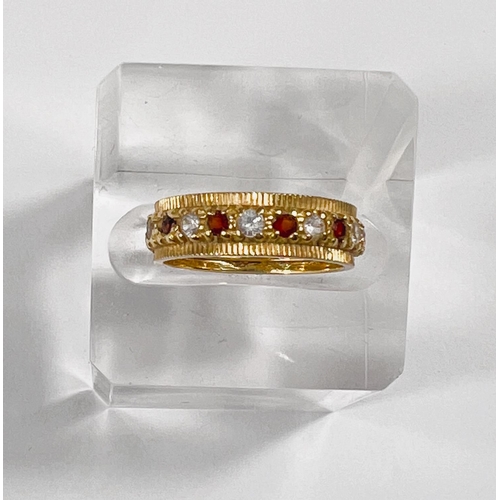 734 - An 18 carat hallmarked gold eternity ring set alternating red and clear stones