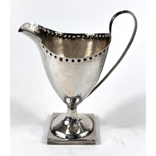 735 - A Georgian classical-style helmet-shaped, hallmarked silver pedestal cream jug with punched border a... 