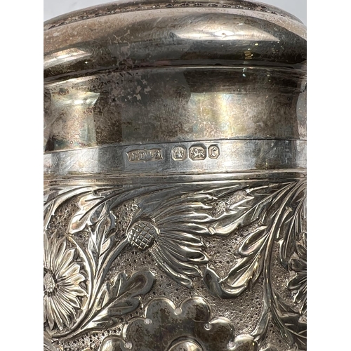 764 - A hallmarked silver cylindrical covered jar with extensive chased and embossed decoration, Sheffield... 