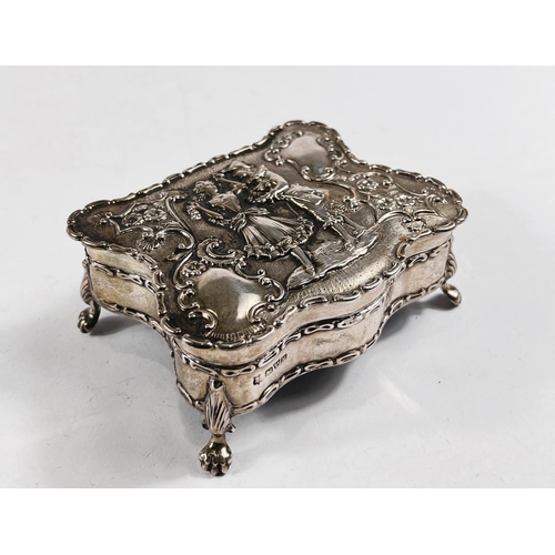 770 - A hallmarked silver shaped rectangular jewellery box, the hinged lid decorated in relief with an 18t... 