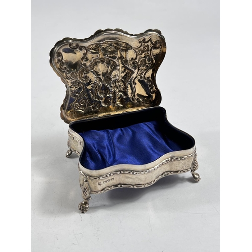 770 - A hallmarked silver shaped rectangular jewellery box, the hinged lid decorated in relief with an 18t... 