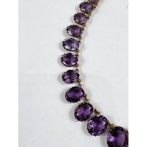 793 - A gilt metal rivière necklace set graduating amethyst coloured stones with shell clasp, stamped 'Nap... 