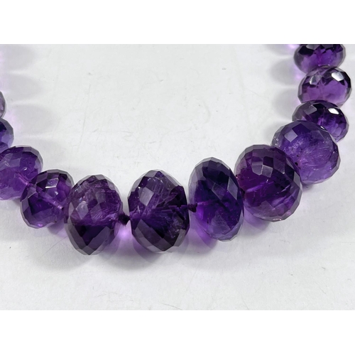 795 - A bead necklace formed from multifaceted graduating amethysts, largest bead diameter 2.5cm, length 5... 