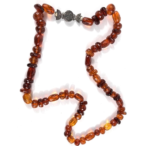 626 - A faceted clear amber necklace of varying shapes and sizes of beads, with white metal clasp with Mid... 