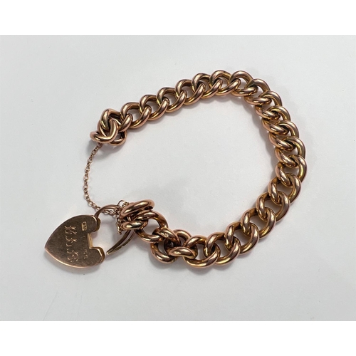 653 - A yellow metal  curb link bracelet, stamped '9', with 9 carat hallmarked gold heart lock, ... 