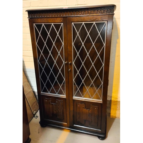 949 - An Ercol modern display cabinet/bookcase with double leaded glass doors over linen fold panel doors