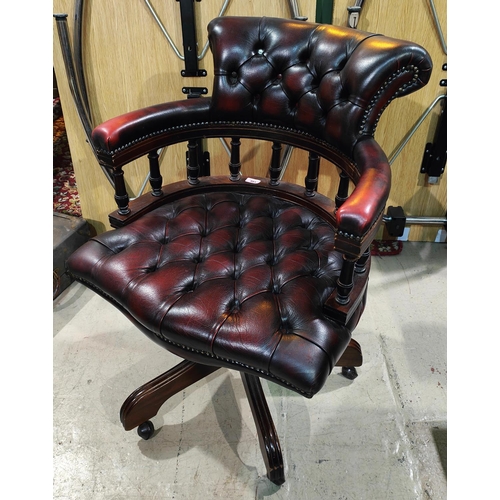 991 - A reproduction swivel armchair in buttoned oxblood hide