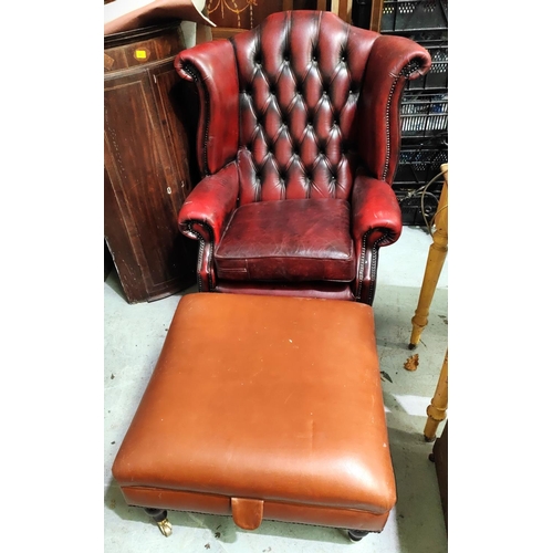 1063 - A modern red leather wing back arm chair with deep button back and a large brown leather effect foot... 